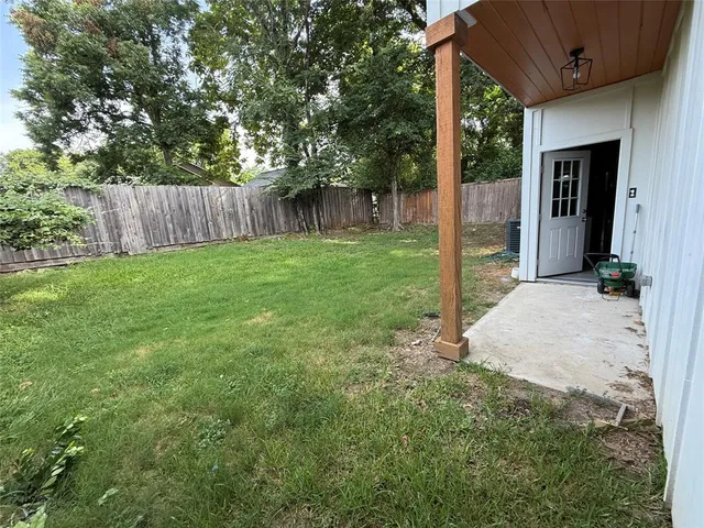 a view of a backyard with large trees and wooden fence