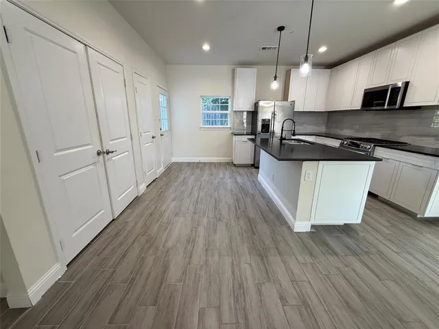 a large kitchen with stainless steel appliances granite countertop a wooden floors