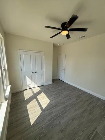 a view of empty room with wooden floor and fan