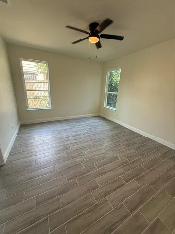 an empty room with wooden floor a ceiling fan and windows