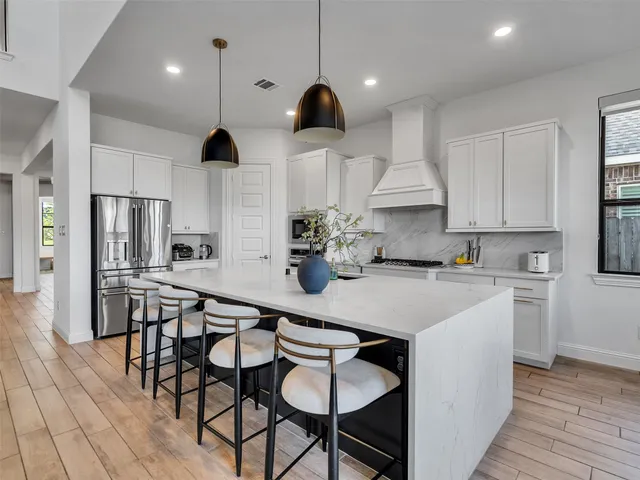 a kitchen with stainless steel appliances a dining table chairs and white cabinets