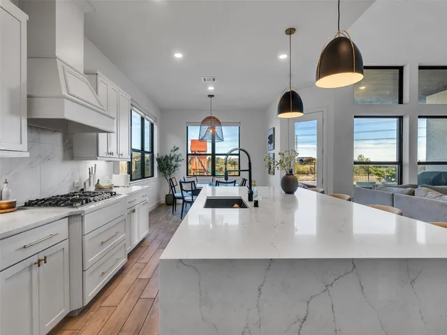 a large kitchen with stainless steel appliances a large counter top a stove a chimney a sink and a large window