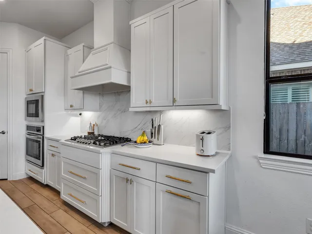 a kitchen with stainless steel appliances granite countertop a stove a sink and white cabinets
