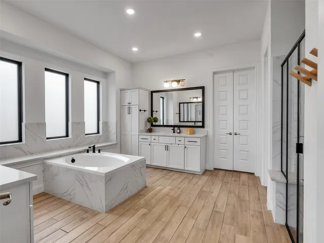 a large white bathroom with a large tub sink and mirror