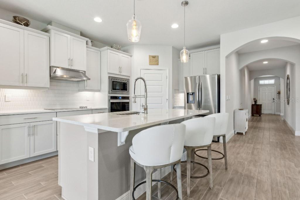 17936 Adrift Road Winter Garden, FL 34787 - Photo 13 of 44 a kitchen with stainless steel appliances granite countertop a stove a sink a refrigerator and white cabinets with wooden floor