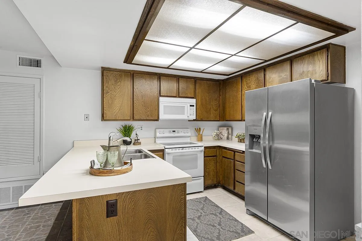 9787 Rimpark Way San Diego, CA 92124 - Photo 10 of 54 a kitchen with a sink a refrigerator and cabinets