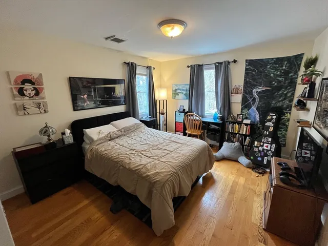 a spacious bedroom with a bed a mirror and dresser