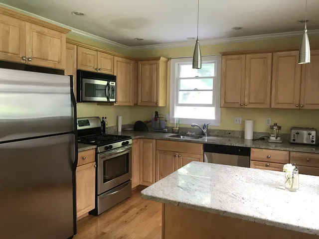 a kitchen with granite countertop a refrigerator stove top oven and sink