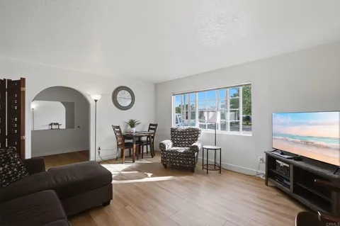 a living room with furniture a large window and wooden floor