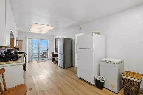a kitchen with a refrigerator a stove top oven a counter space and wooden floor