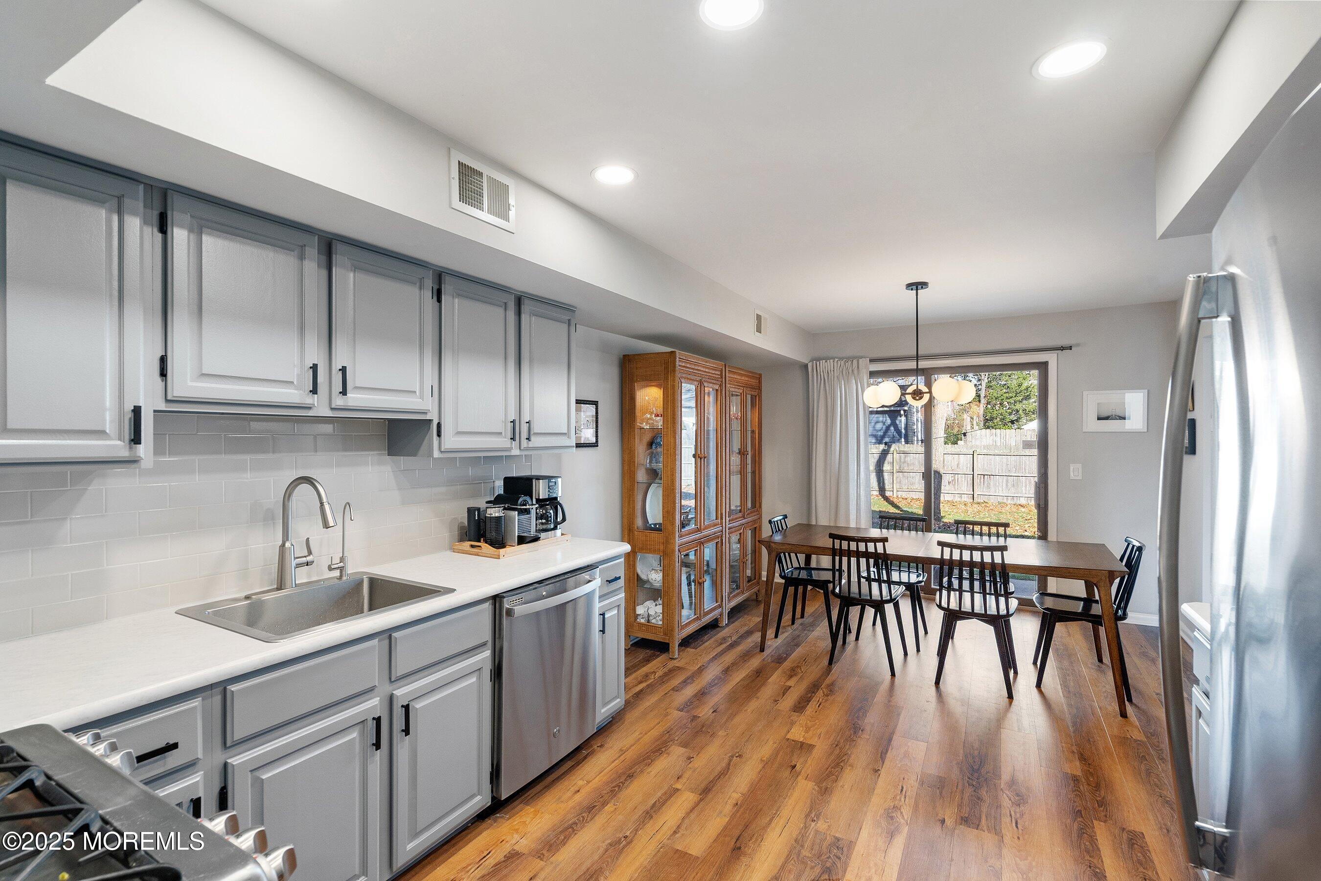 51 White Swan Way Brick, NJ 08723 - Photo 7 of 21 a kitchen with stainless steel appliances a table chairs refrigerator and sink