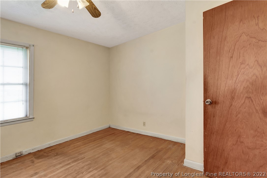 7400 East Raynham Road Fairmont, NC 28340 - Photo 14 of 21 an empty room with a wooden floor and windows