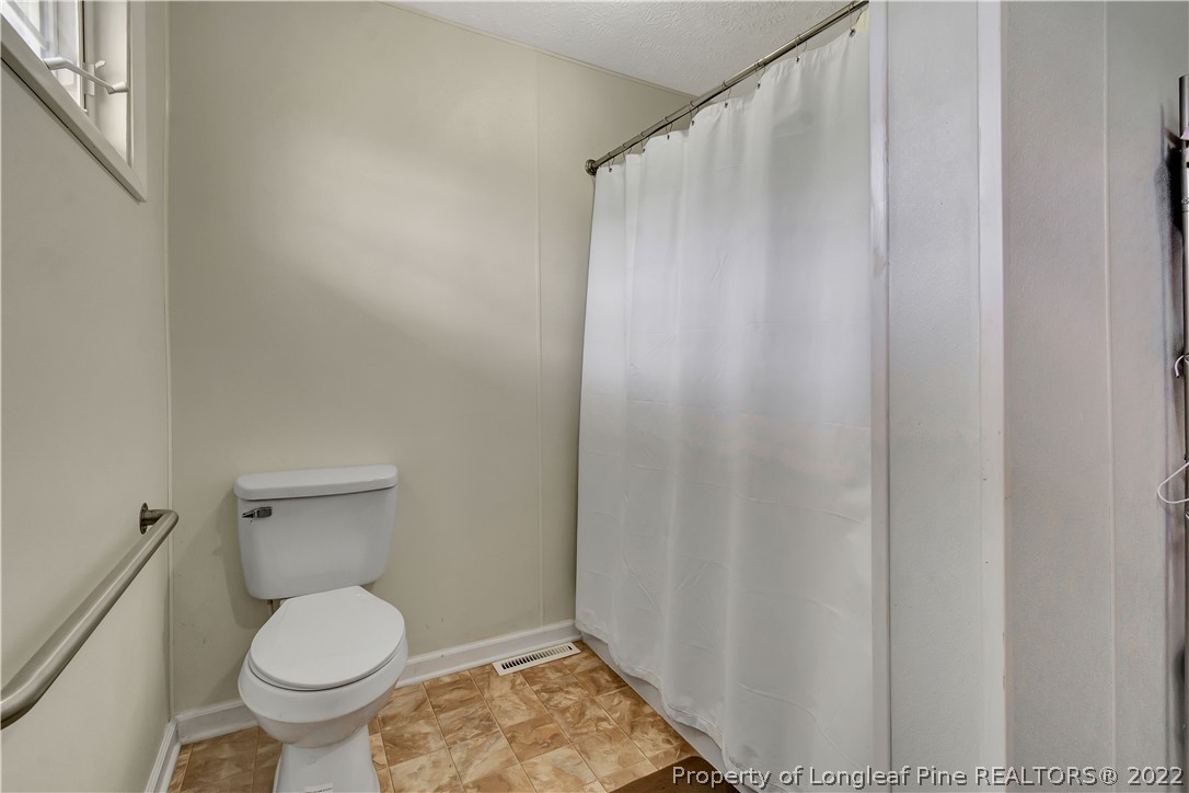 7400 East Raynham Road Fairmont, NC 28340 - Photo 16 of 21 a bathroom with a toilet and a shower curtain