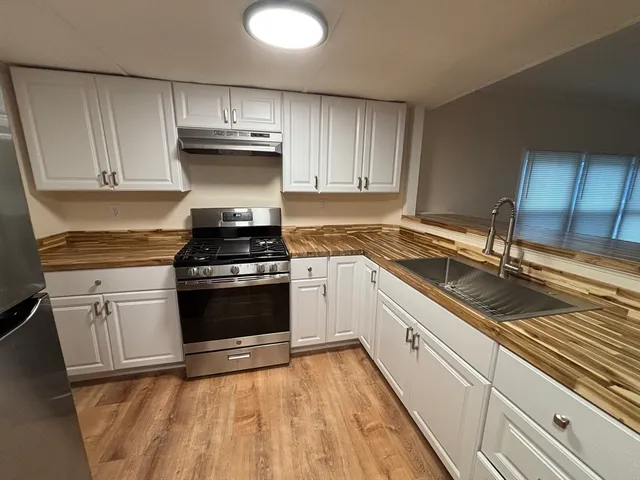 a kitchen with granite countertop a refrigerator and a stove top oven