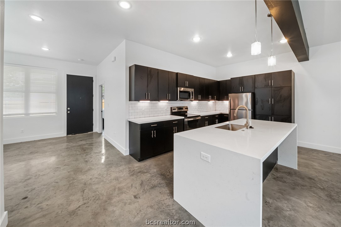 213 Lynn Drive, Unit 202 Bryan, TX 77801 - Photo 3 of 28 a kitchen with kitchen island a sink stainless steel appliances and cabinets