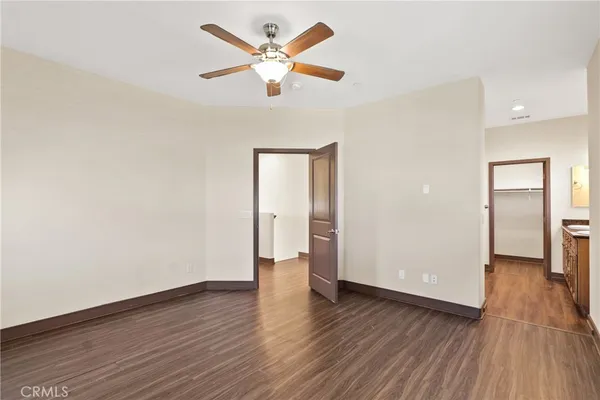 an empty room with wooden floor and a ceiling fan