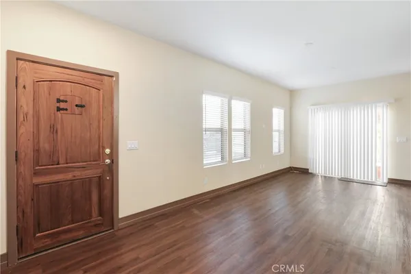 an empty room with wooden floor closet and windows