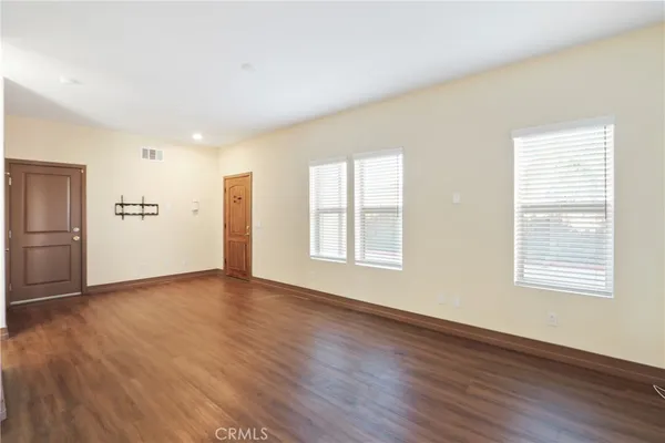 a view of an empty room with a window and wooden floor