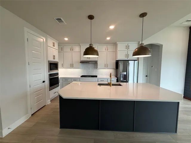 a large kitchen with kitchen island a sink stainless steel appliances and cabinets