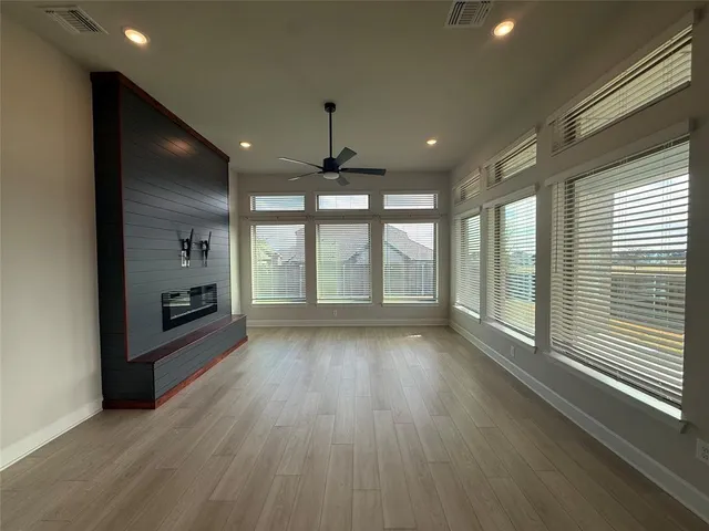 a view of an empty room with a window and wooden floor
