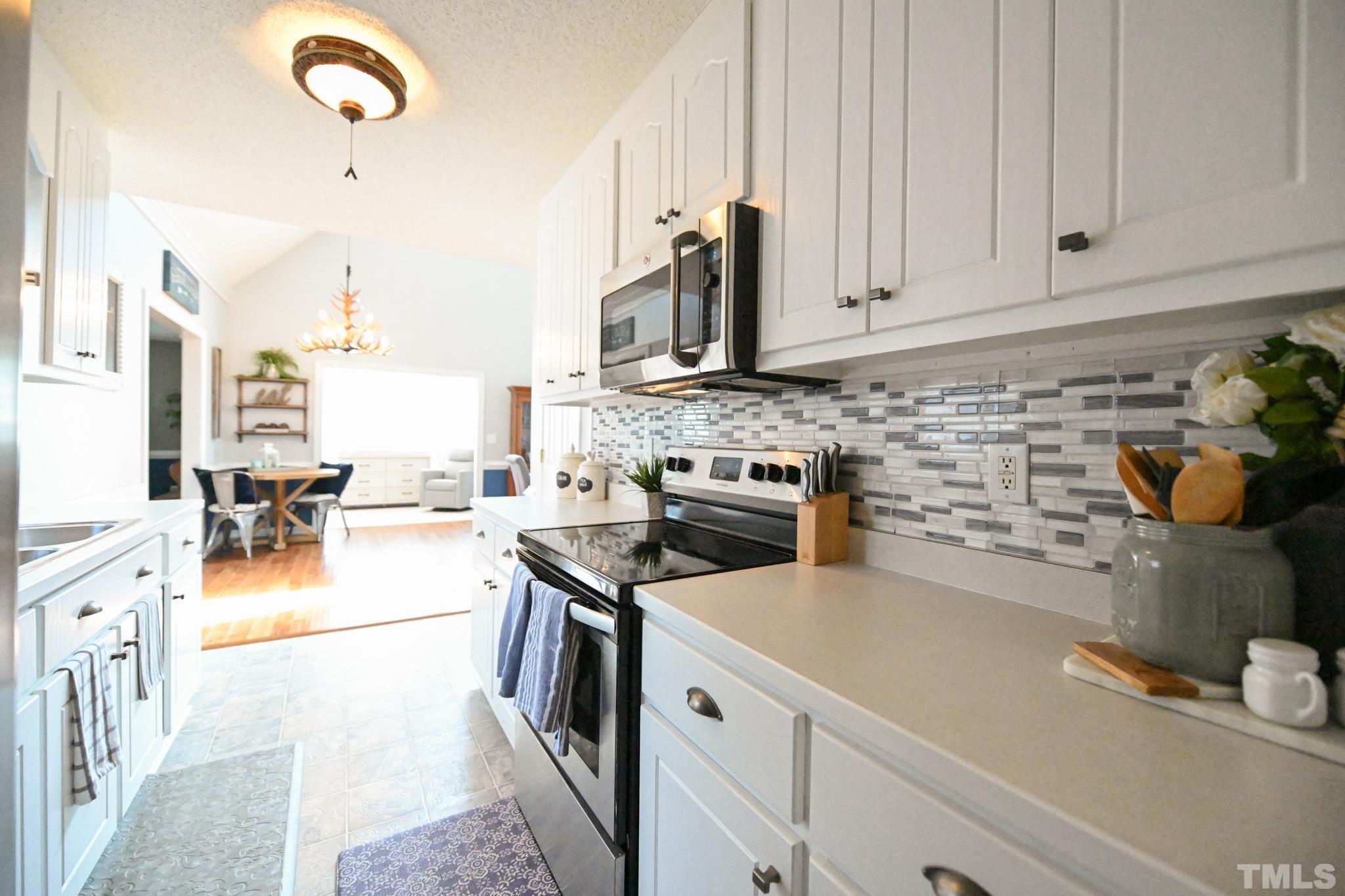 4071 Bizzell Grove Church Road Princeton, NC 27569 - Photo 16 of 53 a kitchen with stainless steel appliances granite countertop a stove a sink dishwasher and white cabinets with wooden floor