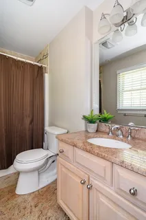 a bathroom with a granite countertop sink a toilet a mirror and shower curtain