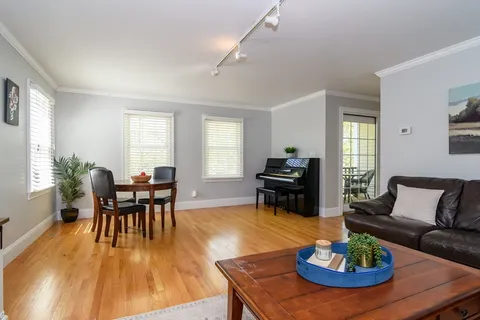 a living room with furniture and a dining table with wooden floor