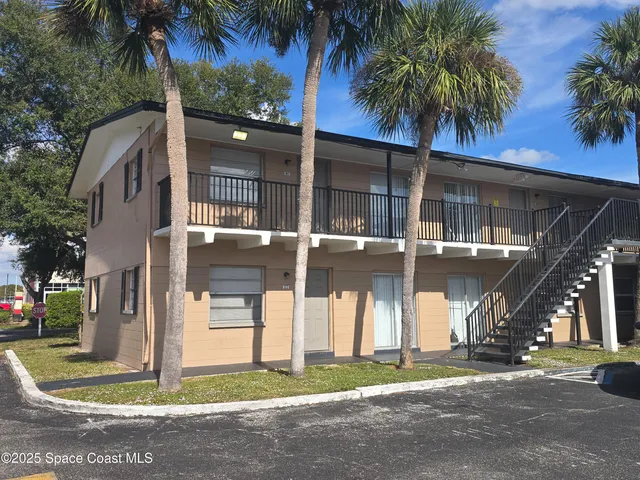 a view of a house with a yard and palm trees