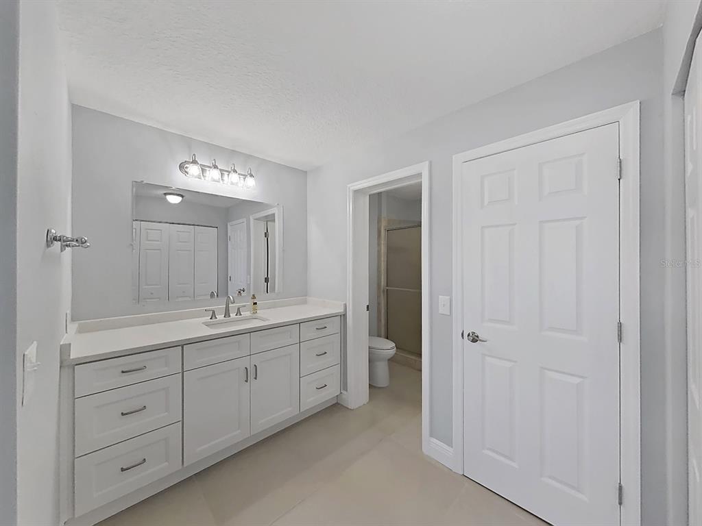 7 Dunoon Place, Unit 104 Dunedin, FL 34698 - Photo 28 of 45 a spacious bathroom with a double vanity sink a large mirror and shower