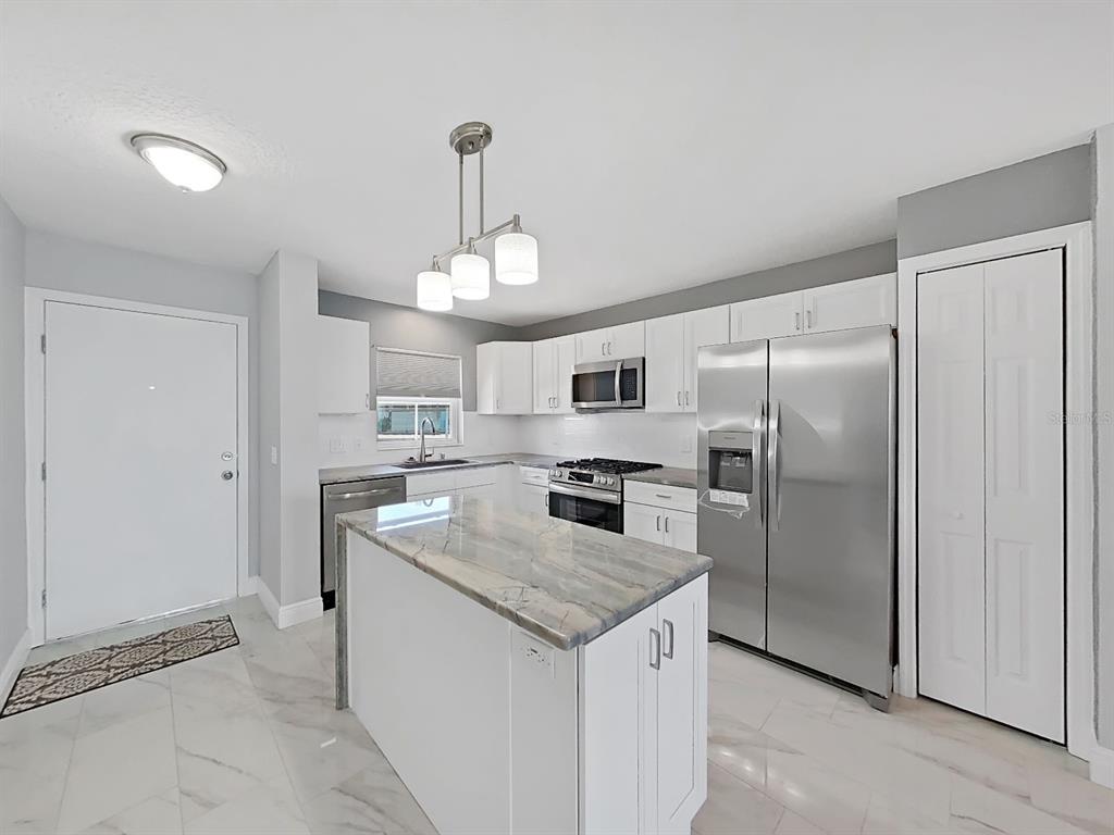 7 Dunoon Place, Unit 104 Dunedin, FL 34698 - Photo 5 of 45 a kitchen with stainless steel appliances granite countertop a refrigerator a stove a sink and a refrigerator