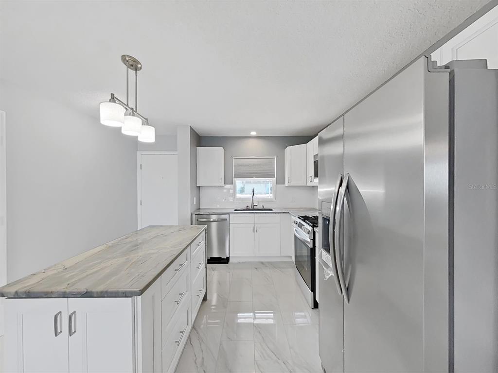 7 Dunoon Place, Unit 104 Dunedin, FL 34698 - Photo 6 of 45 a kitchen with stainless steel appliances granite countertop a refrigerator a sink dishwasher a stove and white cabinets with wooden floor