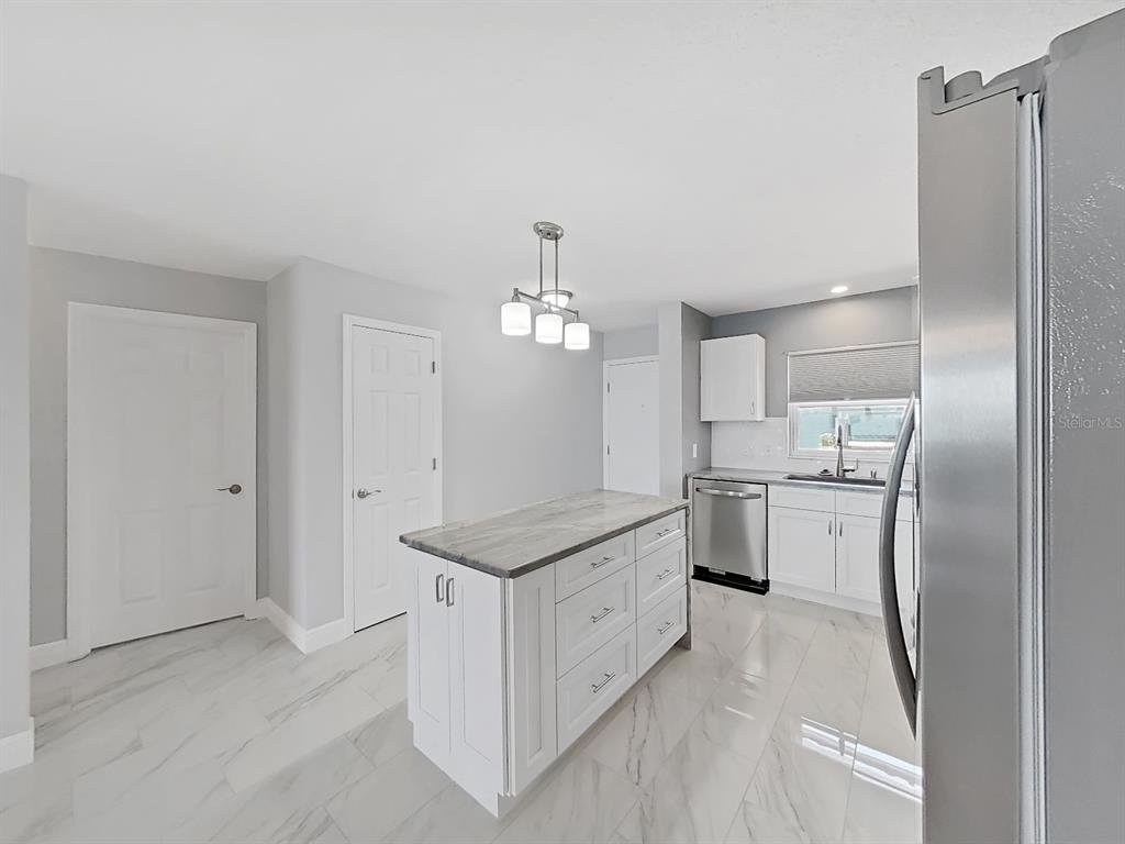 7 Dunoon Place, Unit 104 Dunedin, FL 34698 - Photo 7 of 45 a kitchen with white cabinets and stainless steel appliances