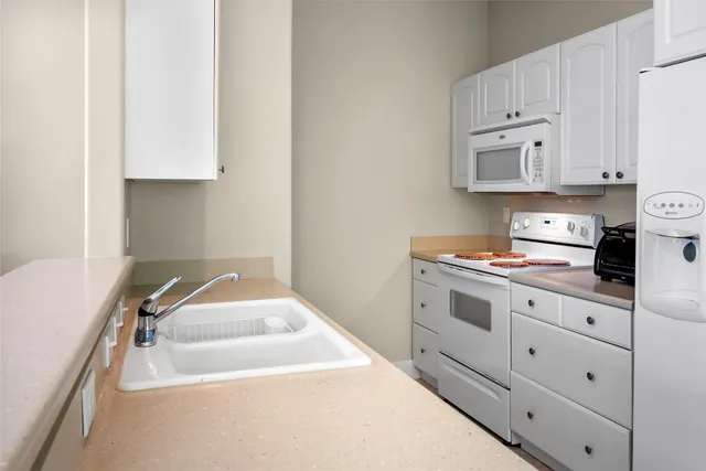 a kitchen with white cabinets and white appliances