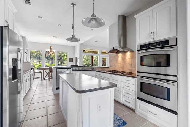 a kitchen with stainless steel appliances granite countertop a stove a sink and a refrigerator