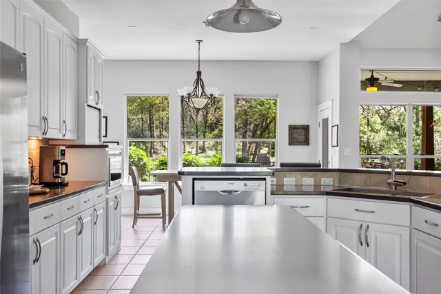 a kitchen with kitchen island granite countertop a stove a sink a counter space and living room view