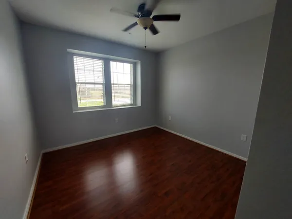 an empty room with wooden floor and chandelier fan