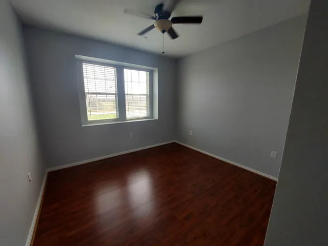 an empty room with wooden floor and chandelier fan