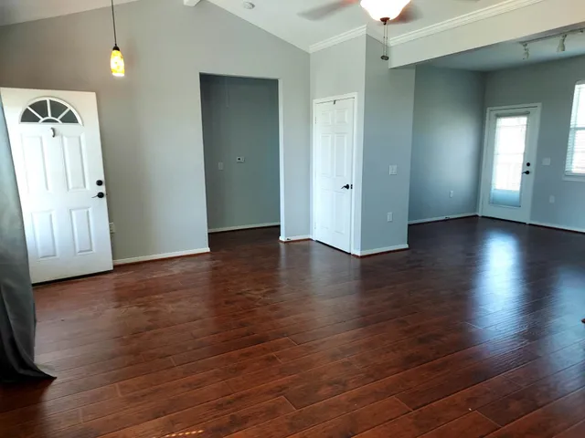 an empty room with wooden floor and windows