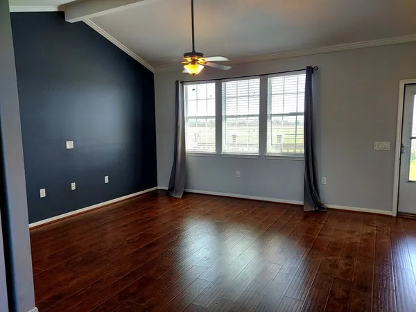 a view of an empty room with wooden floor and a window