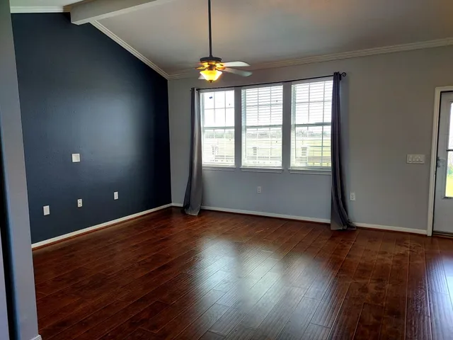 a view of an empty room with wooden floor and a window