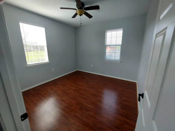 an empty room with wooden floor and a ceiling fan