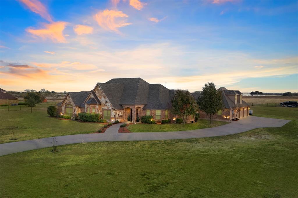 French country home with a front lawn, stone siding, and driveway