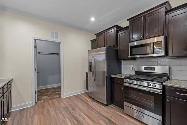 a kitchen with stainless steel appliances granite countertop a refrigerator a stove and a sink with wooden floors