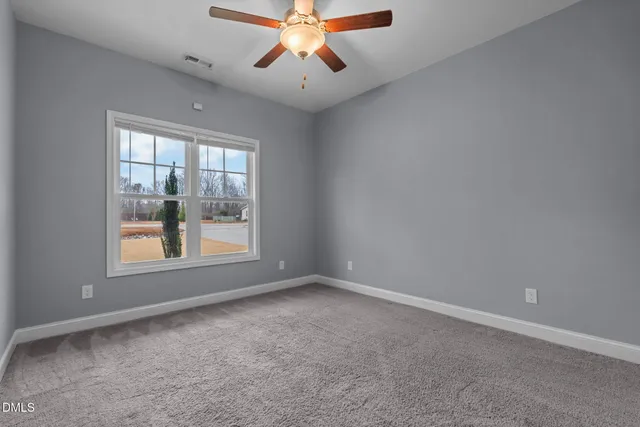 a view of an empty room with window and a chandelier fan
