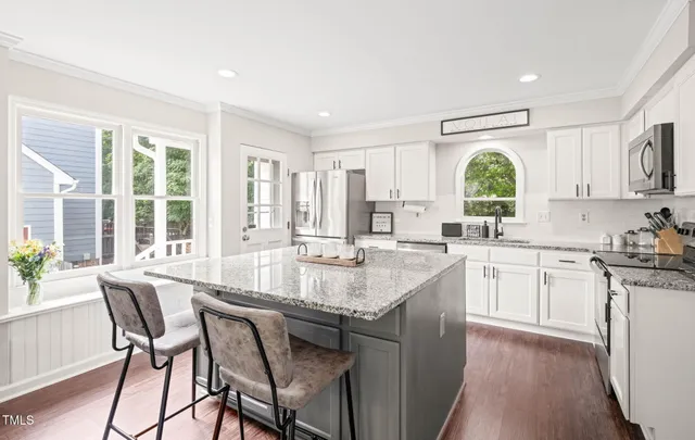 a large kitchen with kitchen island granite countertop a large window and white cabinets