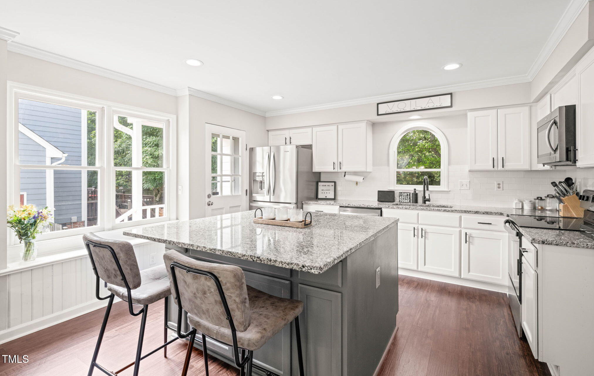 a large kitchen with kitchen island granite countertop a large window and white cabinets