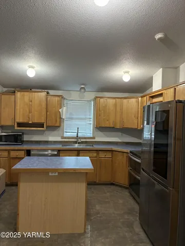 a kitchen with stainless steel appliances granite countertop a sink and a refrigerator