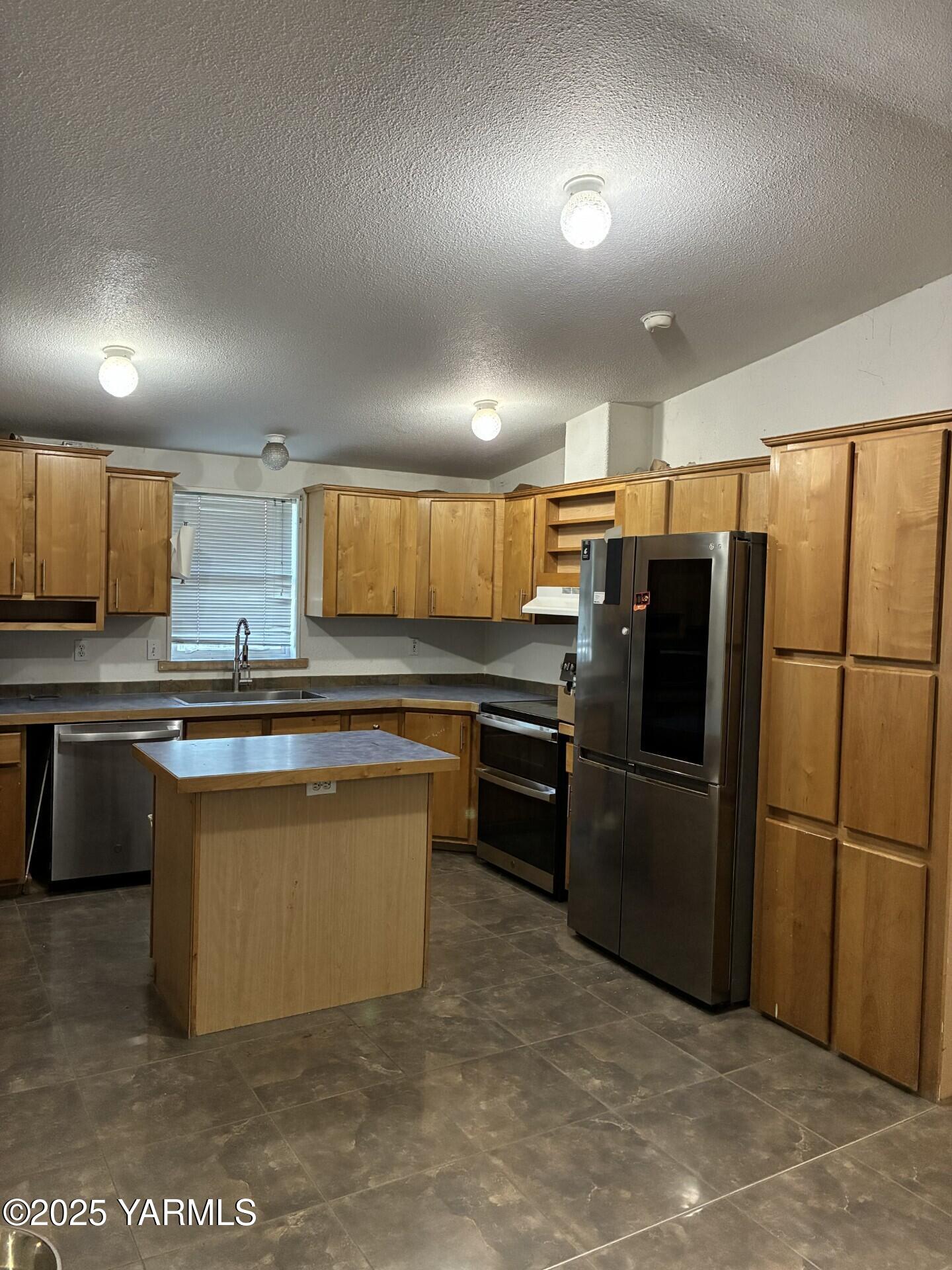 605 Dean Avenue Granger, WA 98932 - Photo 10 of 27 a kitchen with stainless steel appliances granite countertop a refrigerator a stove a sink and a microwave