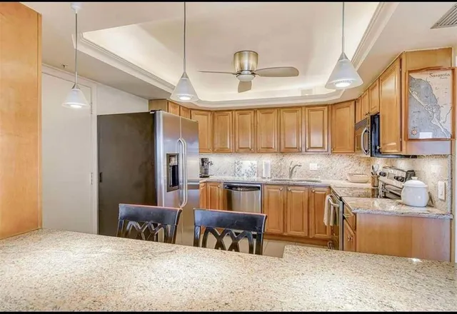 a kitchen with stainless steel appliances granite countertop a sink refrigerator and cabinets