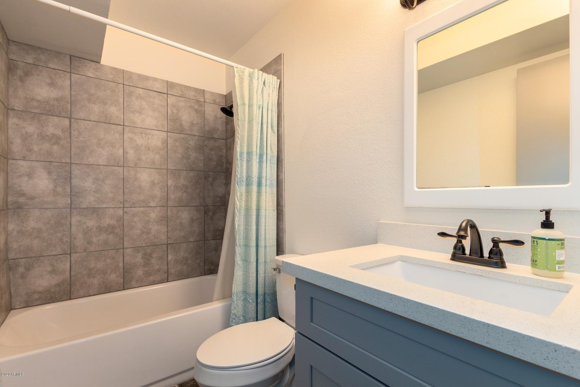 2439 East Riviera Drive Tempe, AZ 85282 - Photo 28 of 40 a bathroom with a sink a toilet a mirror a bathtub and shower